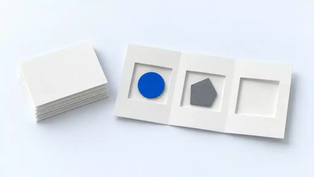 Ein Stapel weißer Seiten neben einem gefalteten Blatt mit blauem und grauem Inhaltsteil und einem leeren Feld. (KI-generiert)