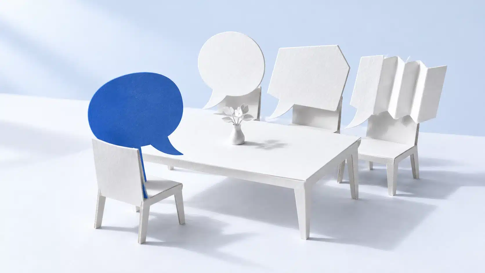 Eine blaue Papier-Sprechblase sitzt drei unterschiedlich gefalteten weißen Sprechblasen gegenüber.