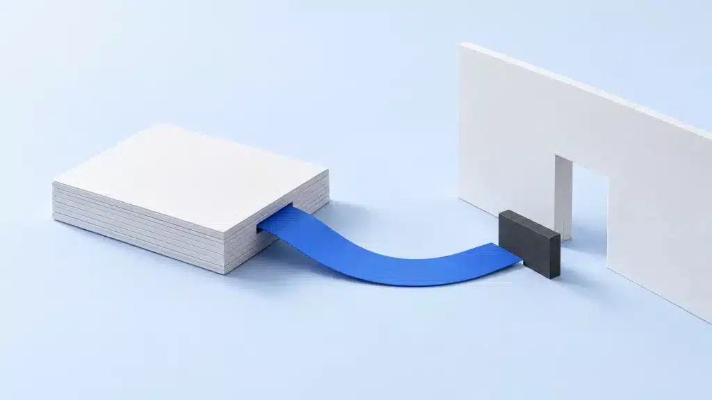 Aus einem weißen Kartonstapel führt ein blaues Papierband zu einer Öffnung in einer weißen Wand. Ein dunkler Riegel stoppt das Band davor. (KI-generiert)